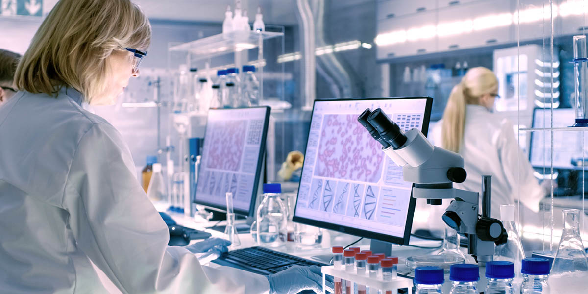 Senior Female Scientist Works with High Tech Equipment in a Modern Laboratory. Her Colleagues are Working Beside Her.